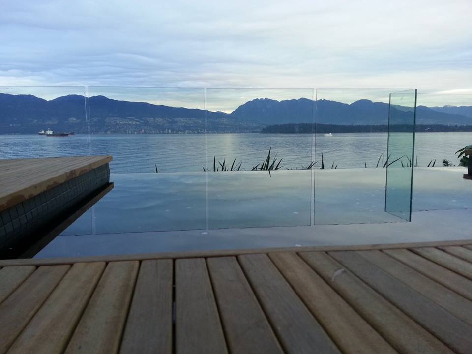 Enjoy a serene waterfront retreat with a custom wooden deck overlooking crystal-clear water and a distant boat—perfect for peaceful moments.