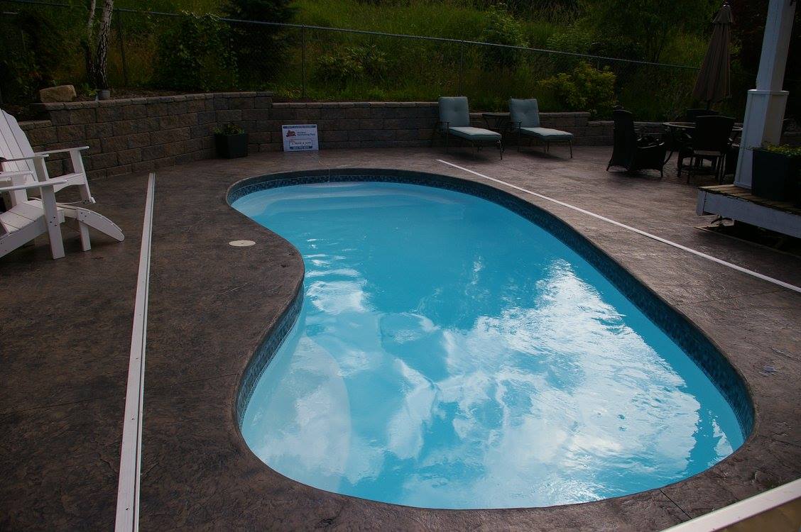 Enjoy the crisp, clear waters of our fiberglass S-shaped in-ground pool, surrounded by a sunlit patio and lush greenery—perfect for a summer of relaxation.
