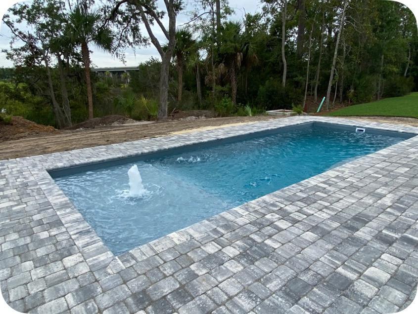 Experience tranquil backyard luxury with our rectangular fiberglass pool, set amid stone decking and lush landscaping.