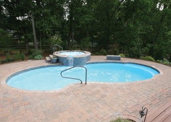 San Juan fiberglass in‑ground pool with spa in a tree‑lined backyard