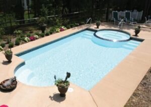 Fiberglass inground pool with spa in a landscaped backyard