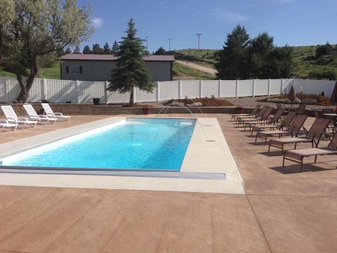 Rectangular fiberglass pool with clear turquoise water in a sunny backyard.