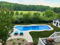 Finished freeform fiberglass pool with turquoise water in a backyard setting.