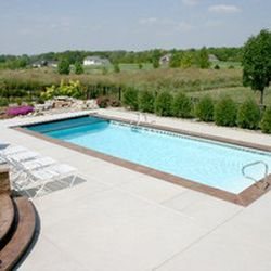 Fiberglass inground pool with turquoise water and tanning ledge in a sunny backyard
